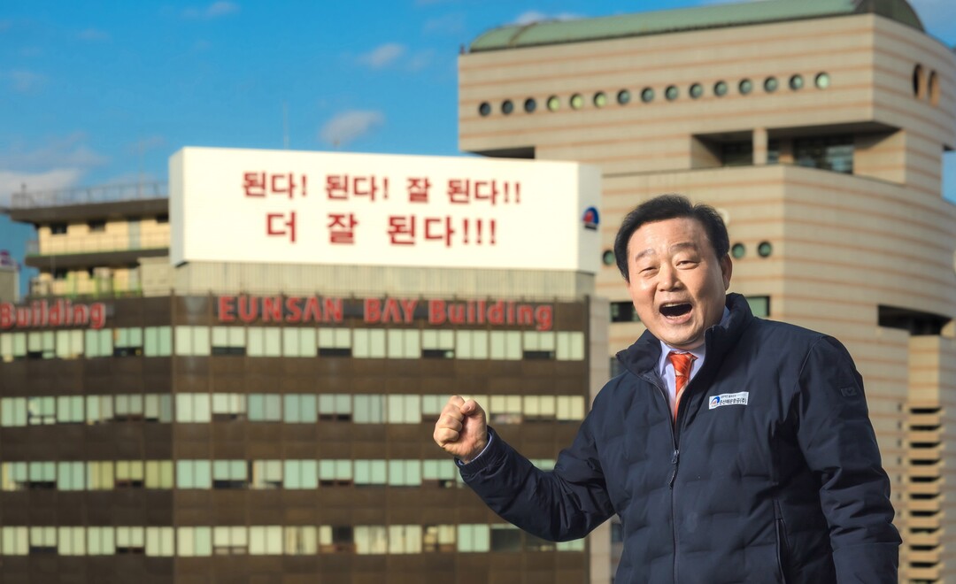 은산해운항공㈜ 양재생 회장이 은산그룹의 상징인 부산 중구 중앙동 소재 은산베이빌딩을 배경으로 그룹의 슬로건인 “된다. 된다. 잘 된다. 더 잘 된다”를 외치며 포즈를 취하고 있다.   은산해운항공 제공