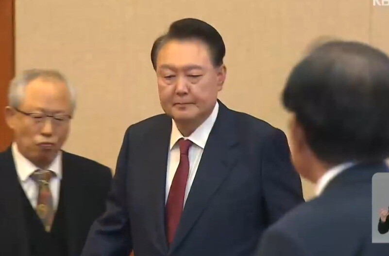 윤석열 대통령이 지난 23일 오후 헌법재판소에서 열린 탄핵심판 4차 변론기일에 출석, 변호인들이 지켜보는 가운데 자신의 좌석으로 향하고 있다. kbs 뉴스속보 화면 갈무리