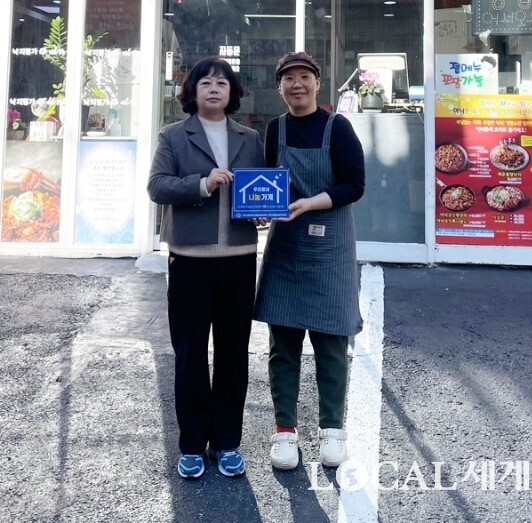 부산 북구 만덕3동행정복지센터 동장(왼쪽) 13일 관내 음식점 ‘아낙촌 만덕점’을 방문, 가게 앞에서 ‘우리동네 나눔가게’ 현판을 전달하며 기념촬영을 하고 있다. 북구청 제공