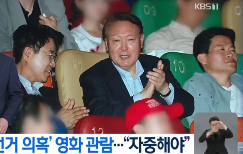 윤석열 대통령이 21일 한국사 강사 전한길(오른쪽) 씨의 초청으로 부정선거의혹을 다룬 다큐멘터리 영화를 보러 모 극장에 공개리에 모습을 드러냈다. 중앙선관위는 이에 대해 바람직하지 않은 행동이라고 비판했다.  KBS 뉴스화면 갈무리