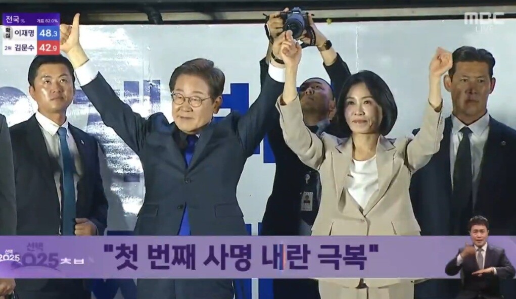 제21대 대통령 당선된 더불어민주당 이재명 대선 후보가 당선이 확실시되던 4일 오전 1시 30분경 서울 여의도 국회 인근에서 당 주최로 열린 국민개표방송 행사에 참석해 연설한 뒤 부인 김혜경 여사와 함께 손을 들어 인사하고 있다. MBC 대선 개표 방송 화면 캡처