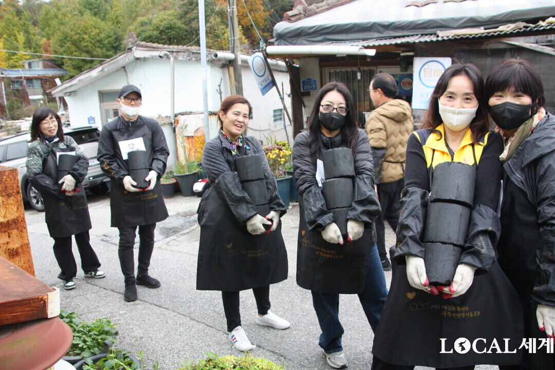 연탄을 각각 두 장, 세 장씩 들고 줄을 이어 가파른 길을 오르며 나르고 있다.