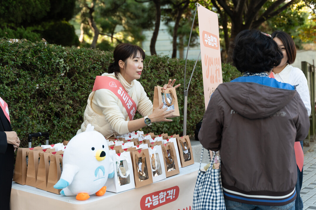 안드레교회 봉사자들이 11일 안드레연수원 인근에서 좌판을 펼쳐놓고 지역주민들에게 수제 쿠키와 빼빼로가 든 기프트백을 한 여성주민에게 나눠주며 대화하고 있다. 신천지 안드레교회 제공