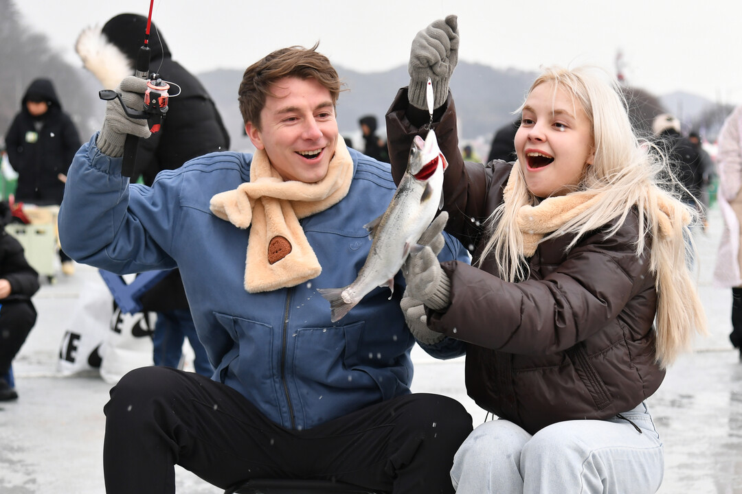얼음낚시로 산천어를 잡고 기뻐하는 외국인 관광객