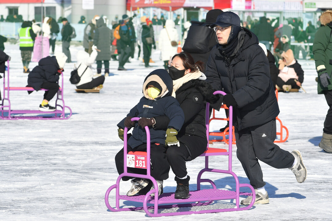 가족 단위 관광객들이 얼음썰매 체험을 즐기며 축제를 만끽하고 있다