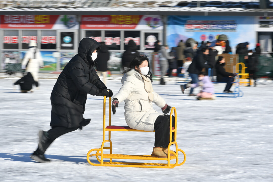 가족 단위 관광객들이 얼음썰매 체험을 즐기며 축제를 만끽하고 있다