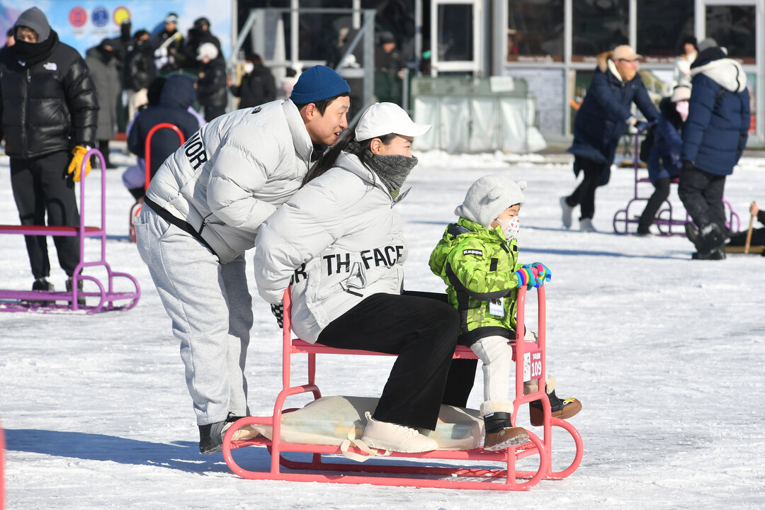 가족 단위 관광객들이 얼음썰매 체험을 즐기며 축제를 만끽하고 있다