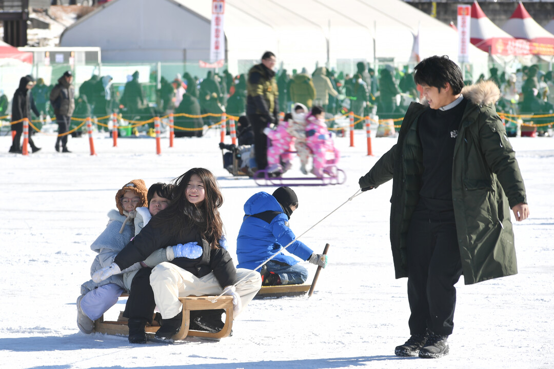 가족 단위 관광객들이 얼음썰매 체험을 즐기며 축제를 만끽하고 있다