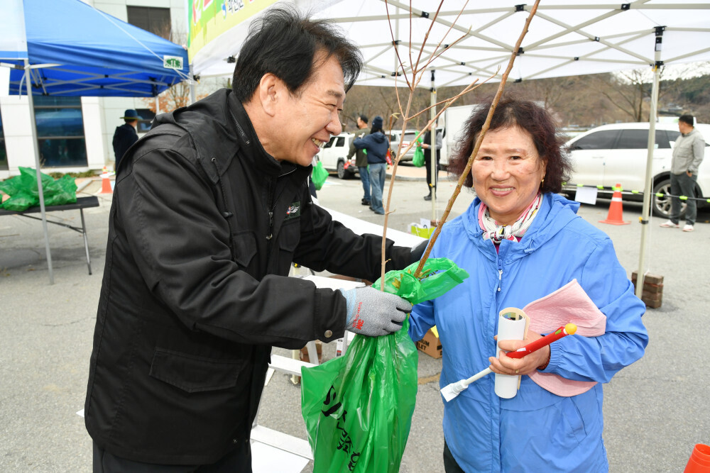 류희상 군의장(왼쪽)가  &lsquo;나무 나눠주기 행사&rsquo;에 참여한 주민에게 나무를 전달하고 있다(화천군의회 제공)