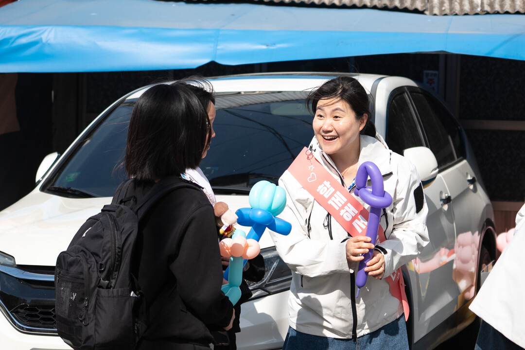 신천지 안드레교회 소속 한 자원봉사자가 지난 4일 부산 동구 일대에서 어린이날을 앞두고 환한 표정으로 학생들에게 아트 풍선과 간식을 전달하며 대화하고 있다. &nbsp;이하 신천지 안드레교회 제공