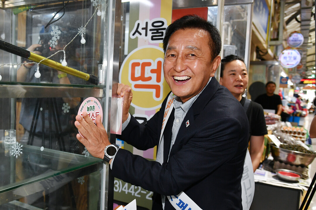 김세훈 군수가 화천시장 업소를 방문해 &lsquo;기본소득 가맹점&rsquo;스티커를 부착하고 있다(화천군청 제공)