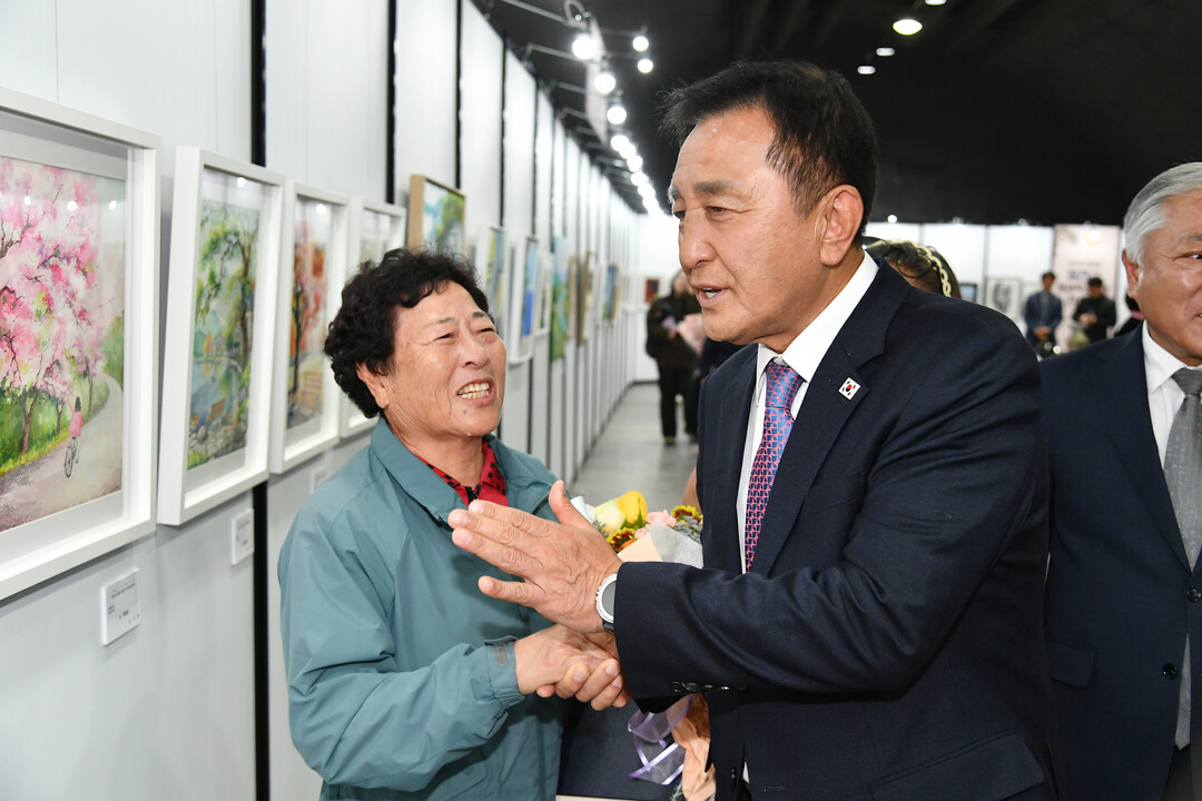 지난 23일 화천군 화천읍 서화산 다목적 광장에서 열린 2026년 제3회 화천군 평생학습축제에서 김세훈 화천군수가 시화전에 출품한 이태선 어르신(간동노인대학)을 격려하고 있다(화천군청 제공)